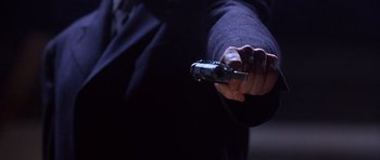 Movie still from “The Usual Suspects” (1995), directed by Bryan Singer – A person holding a remote control in their hand; Extreme Close Up shot, Low angle