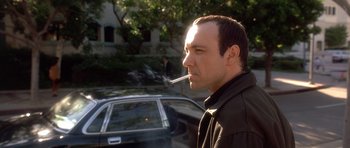 Movie still from “The Usual Suspects” (1995), directed by Bryan Singer – A man smoking a cigarette while standing next to a car; Close Up shot, Low angle