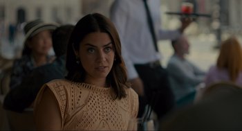 Movie still from “Confess, Fletch” (2022), directed by Greg Mottola – A woman in a tan top is looking at the camera; Close Up shot, Over the shoulder angle