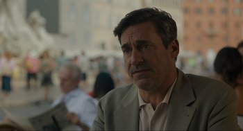 Movie still from “Confess, Fletch” (2022), directed by Greg Mottola – A person wearing a suit and tie; Close Up shot, Over the shoulder angle