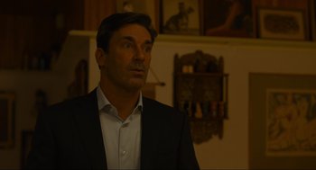 Movie still from “Confess, Fletch” (2022), directed by Greg Mottola – A person wearing a suit and tie; Medium shot, Over the shoulder angle