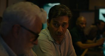 Movie still from “Confess, Fletch” (2022), directed by Greg Mottola – A man sitting in front of another man in front of another man; Close Up shot, Over the shoulder angle