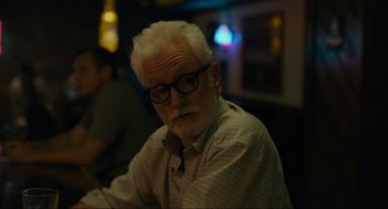 Movie still from “Confess, Fletch” (2022), directed by Greg Mottola – An older man with white hair wearing glasses; Close Up shot, Over the shoulder angle