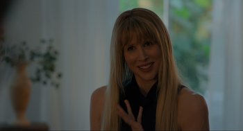 Movie still from “Confess, Fletch” (2022), directed by Greg Mottola – A woman with long blonde hair smiling for the camera; Close Up shot, Over the shoulder angle