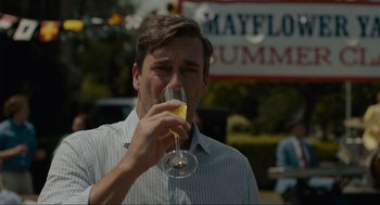 Movie still from “Confess, Fletch” (2022), directed by Greg Mottola – A man holding a glass of wine in his hand; Close Up shot, Over the shoulder angle