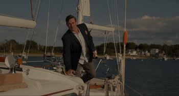 Movie still from “Confess, Fletch” (2022), directed by Greg Mottola – A man standing on the side of a sail boat; Medium shot, Low angle