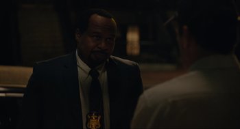 Movie still from “Confess, Fletch” (2022), directed by Greg Mottola – A man in a suit and a tie; Close Up shot, Over the shoulder angle