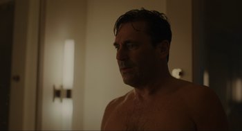 Movie still from “Confess, Fletch” (2022), directed by Greg Mottola – A man with wet hair is standing in a bathroom; Close Up shot, Over the shoulder angle