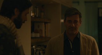 Movie still from “Confess, Fletch” (2022), directed by Greg Mottola – A man and a woman are talking in a kitchen; Medium shot, Over the shoulder angle