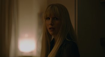 Movie still from “Confess, Fletch” (2022), directed by Greg Mottola – A woman with long blonde hair standing next to a wall; Close Up shot, Over the shoulder angle