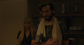 Movie still from “Confess, Fletch” (2022), directed by Greg Mottola – A man and a woman standing next to each other in a room; Medium shot, Over the shoulder angle