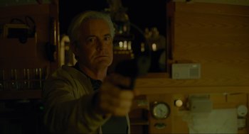 Movie still from “Confess, Fletch” (2022), directed by Greg Mottola – A man holding a gun in a room; Close Up shot, Low angle