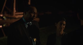 Movie still from “Confess, Fletch” (2022), directed by Greg Mottola – A man and a woman standing next to each other in the dark; Close Up shot, Over the shoulder angle