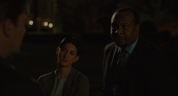 Movie still from “Confess, Fletch” (2022), directed by Greg Mottola – A man and a woman standing next to each other in the dark; Close Up shot, Over the shoulder angle
