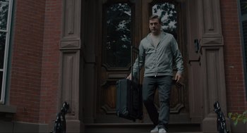 Movie still from “Confess, Fletch” (2022), directed by Greg Mottola – A man walking down the street holding a suitcase; Medium shot, Low angle