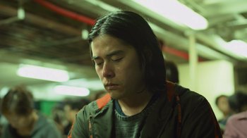 Movie still from “Contagion” (2011), directed by Steven Soderbergh – A man with long black hair is looking down; Close Up shot, Low angle