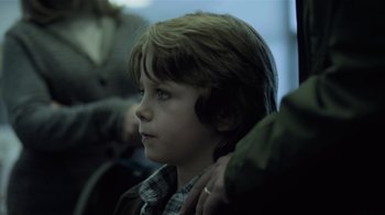 Movie still from “Contagion” (2011), directed by Steven Soderbergh – A young boy sitting on a train looking off to the side; Close Up shot, Over the shoulder angle