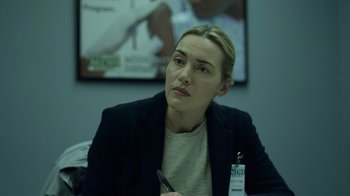 Movie still from “Contagion” (2011), directed by Steven Soderbergh – A person sitting at a table holding a pen; Close Up shot, Over the shoulder angle