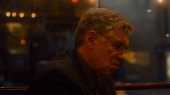 Movie still from “Contagion” (2011), directed by Steven Soderbergh – An older man wearing glasses and a suit; Close Up shot, Over the shoulder angle