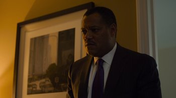 Movie still from “Contagion” (2011), directed by Steven Soderbergh – A man wearing a suit and tie in front of a picture; Close Up shot, Low angle
