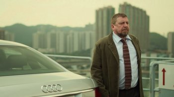 Movie still from “Contagion” (2011), directed by Steven Soderbergh – A man standing next to a car in front of a building; Medium shot, Low angle