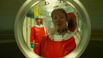 Movie still from “Contagion” (2011), directed by Steven Soderbergh – A woman in a red coat and a red helmet; Medium shot, Over the shoulder angle