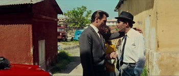 Movie still from “Contempt” (1963), directed by Jean-Luc Godard – A man in a suit and tie talking to another man in a hat and tie; Medium shot, Over the shoulder angle