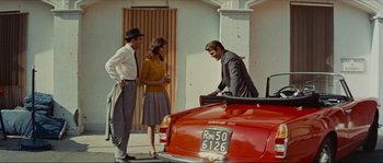 Movie still from “Contempt” (1963), directed by Jean-Luc Godard – A man and two women standing next to a red car; Wide shot, Low angle
