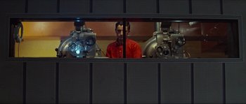 Movie still from “Contempt” (1963), directed by Jean-Luc Godard – A man in a red shirt is looking through a window; Medium shot, Low angle