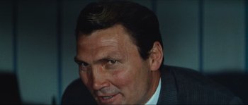 Movie still from “Contempt” (1963), directed by Jean-Luc Godard – A person wearing a suit and tie; Close Up shot, Low angle