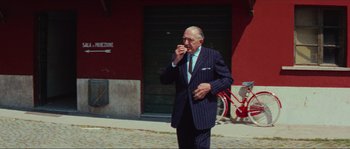 An older man wearing a suit and tie eating something