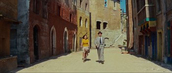 Movie still from “Contempt” (1963), directed by Jean-Luc Godard – A man and a woman riding a bike down a street; Wide shot, Low angle