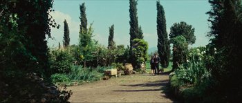 Movie still from “Contempt” (1963), directed by Jean-Luc Godard – Two people standing on a dirt path near a garden; Extreme Wide shot, Low angle