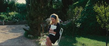 Movie still from “Contempt” (1963), directed by Jean-Luc Godard – A woman sitting on top of a chair holding a book; Wide shot, High angle