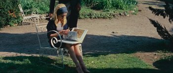 Movie still from “Contempt” (1963), directed by Jean-Luc Godard – A woman sitting on a bench looking at an open book; Medium shot, High angle