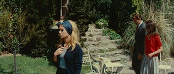 Movie still from “Contempt” (1963), directed by Jean-Luc Godard – A young woman standing in front of a stone staircase; Medium shot, Low angle