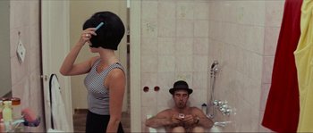 Movie still from “Contempt” (1963), directed by Jean-Luc Godard – A man sitting in a bath tub next to a woman in a bathroom; Medium shot, High angle