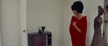 Movie still from “Contempt” (1963), directed by Jean-Luc Godard – A woman standing in front of an old television; Medium shot, High angle