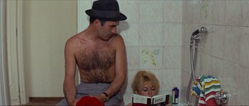 Movie still from “Contempt” (1963), directed by Jean-Luc Godard – A man and woman reading a book in a bathroom; Medium shot, High angle