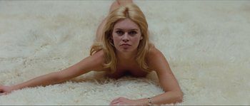 Movie still from “Contempt” (1963), directed by Jean-Luc Godard – A woman laying on the ground with her hands on her stomach; Medium shot, High angle