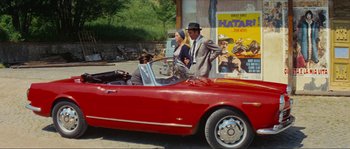 Movie still from “Contempt” (1963), directed by Jean-Luc Godard – A man and a woman are in a red car; Wide shot, Over the shoulder angle