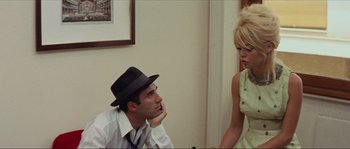 Movie still from “Contempt” (1963), directed by Jean-Luc Godard – A man and a woman sitting next to each other in a room; Medium shot, Low angle