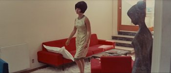 Movie still from “Contempt” (1963), directed by Jean-Luc Godard – A woman in a dress is standing in a living room; Wide shot, Low angle
