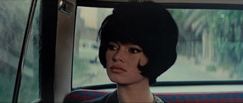 Movie still from “Contempt” (1963), directed by Jean-Luc Godard – A person wearing a wig in a car; Close Up shot, Over the shoulder angle