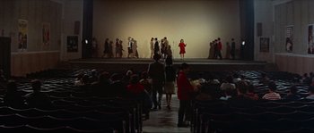 Movie still from “Contempt” (1963), directed by Jean-Luc Godard – A group of people standing in front of a stage; Extreme Wide shot, High angle