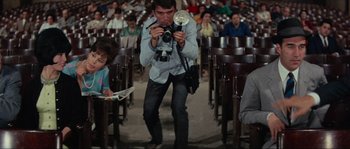 Movie still from “Contempt” (1963), directed by Jean-Luc Godard – A man taking a picture of a crowd of people; Medium shot, Low angle