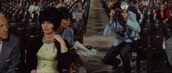 Movie still from “Contempt” (1963), directed by Jean-Luc Godard – A man taking a picture of two women in an audience; Medium shot, High angle