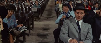 Movie still from “Contempt” (1963), directed by Jean-Luc Godard – A group of people sitting in rows of chairs; Medium shot, Low angle