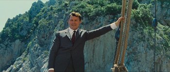 Movie still from “Contempt” (1963), directed by Jean-Luc Godard – A man wearing a suit and tie standing next to a rope; Medium shot, Low angle