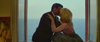 Movie still from “Contempt” (1963), directed by Jean-Luc Godard – A man and a woman kissing near the ocean; Medium shot, High angle